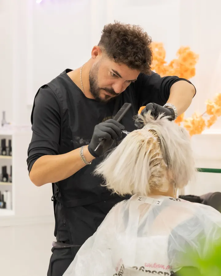 Parrucchiere che applica il colore su capelli biondi